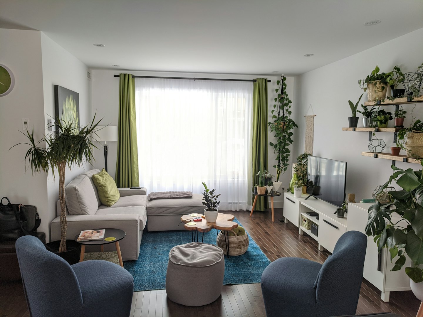 Sala de estar moderna con sofá gris y sillones azules.
