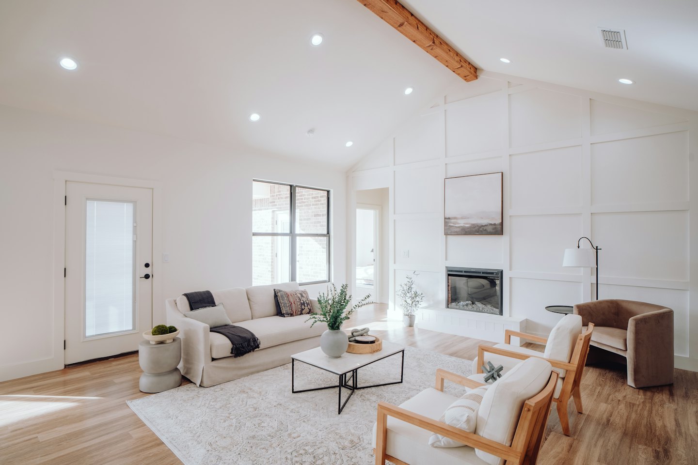 Sala de estar moderna con sofá color crema y sillones de madera.